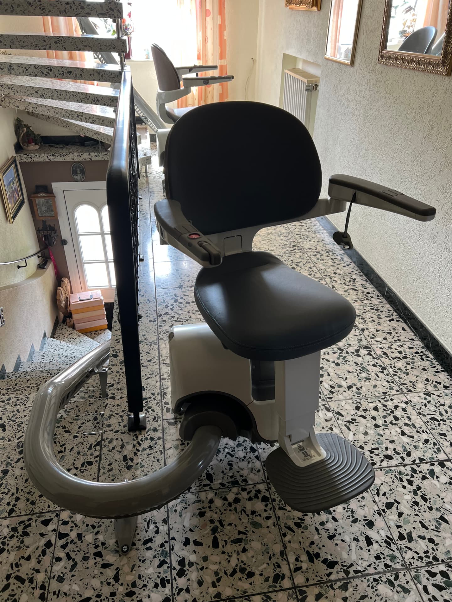 Treppenlift mit dunklem Lederbezug im Flur eines Wohnhauses