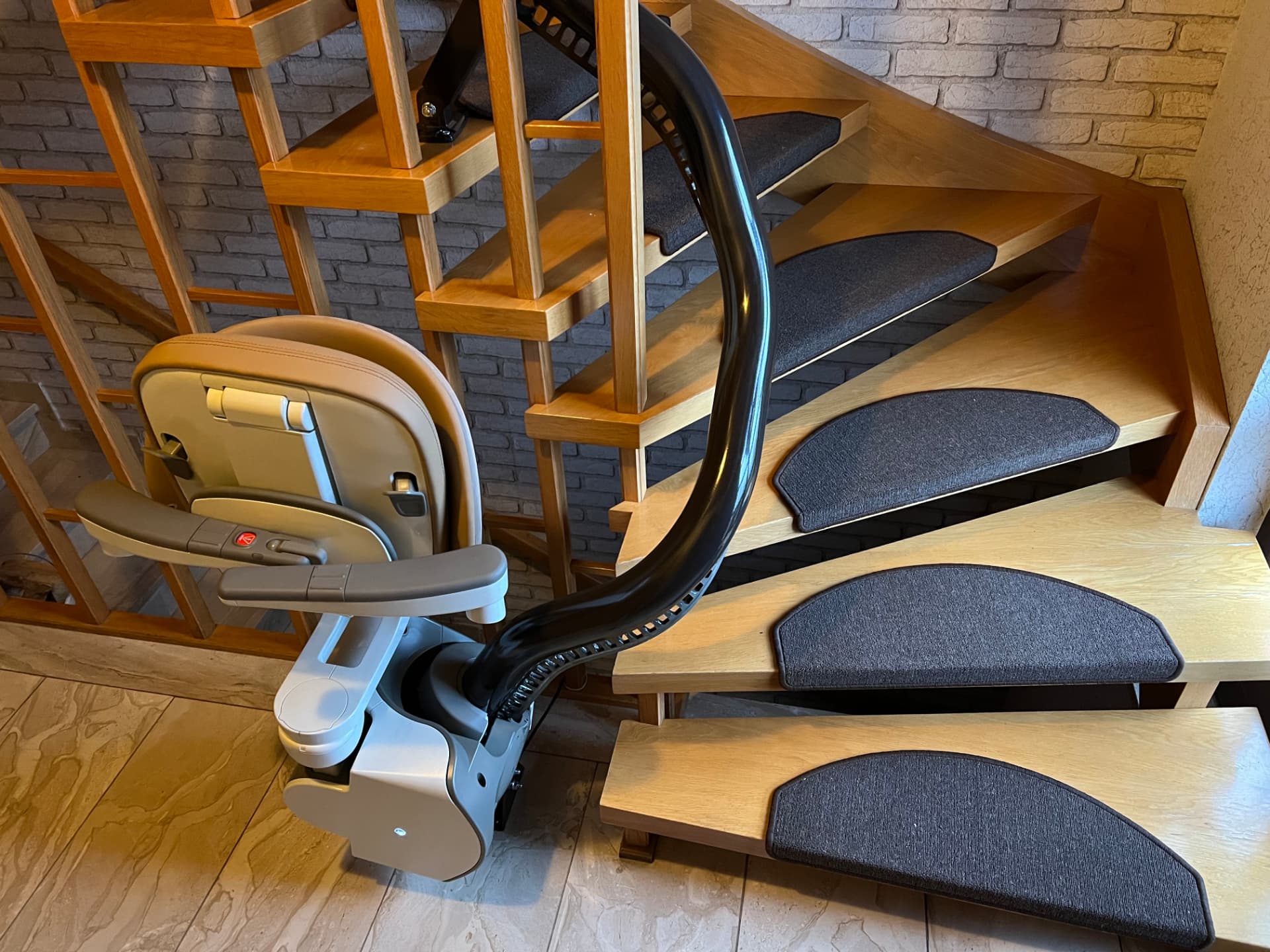 Gebogene Treppenlift-Schiene entlang einer gewendelten Eichentreppe im Wohnhaus