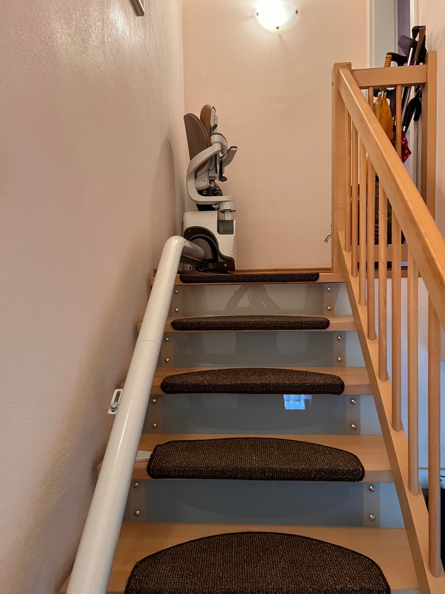 Gerader Treppenlift an einer schmalen Treppe mit Glasgeländer